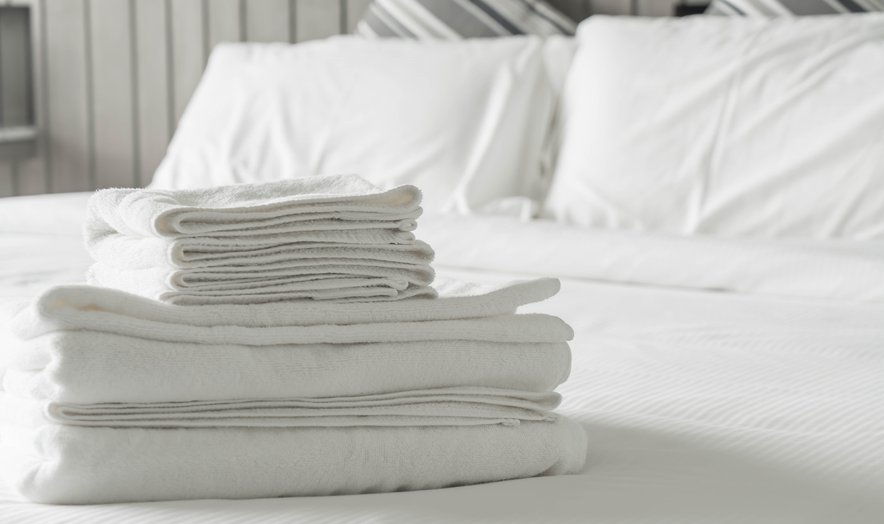 Folded white towels on a made bed