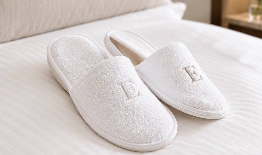 White monogrammed slippers on a bed
